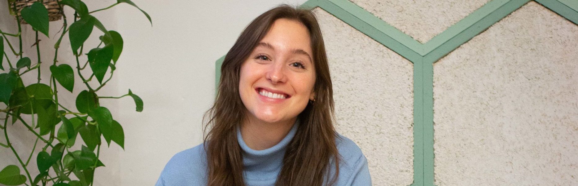 Ronja Kötzer, our new communications support, sitting on a sofa smiling,