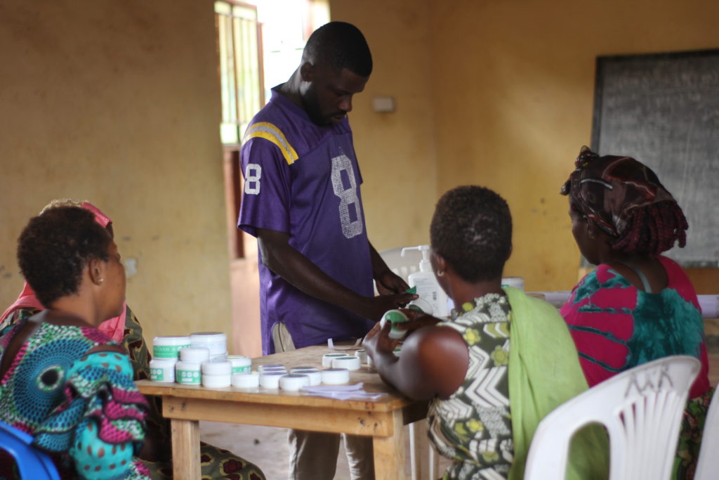 A group of men and women around a table working to manufacture organic insect repellent as part of social or environmental company botanica